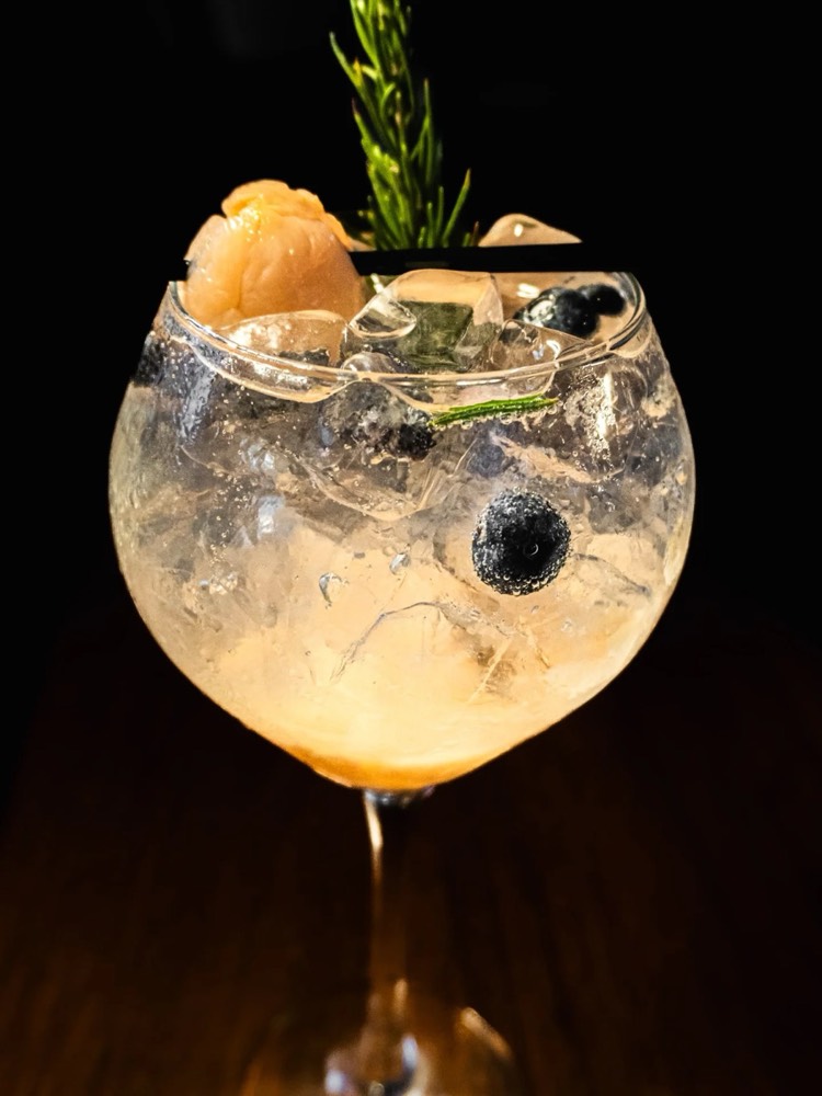 Gin de licha en copa balón con romero y moras