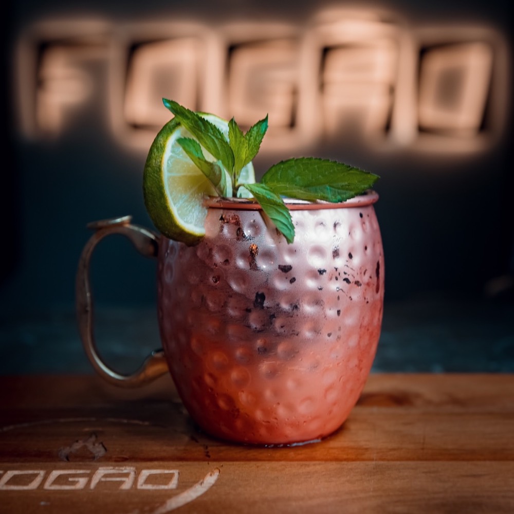 Moscow Mule en taza de cobre frente al letrero FOGÃO