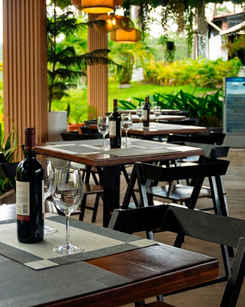 Terraza con mesas, copas y vino frente al jardín